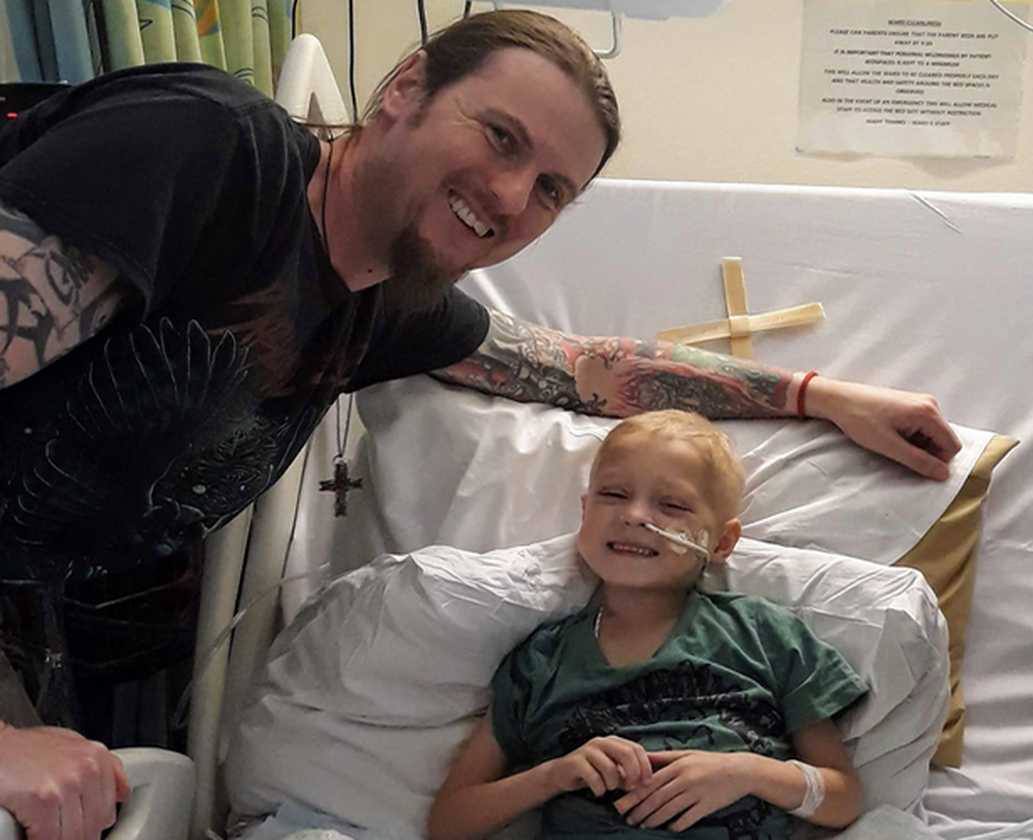 Zakk smiling in his hospital bed during a visit from his dad.