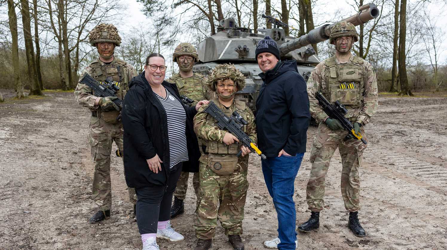 A group photo of Noah, his mum and dad with various army personnel