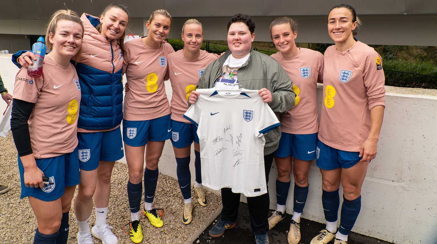 Laura holds her signed England shirt with six of the players alongside her