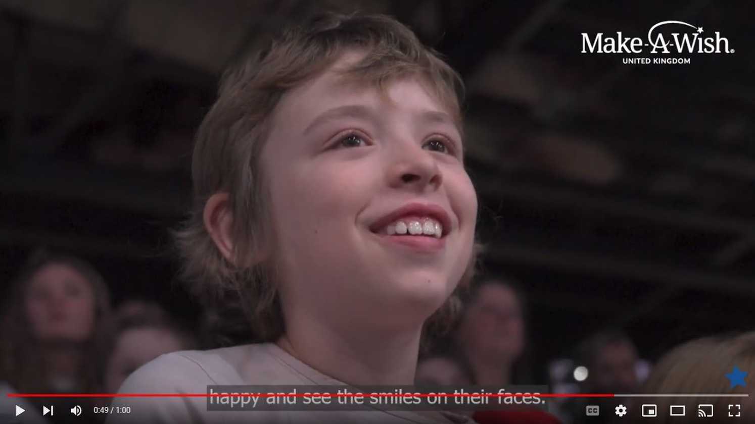 A still from a video of Amber's wish, showing her smiling as she watches an equestrian display.