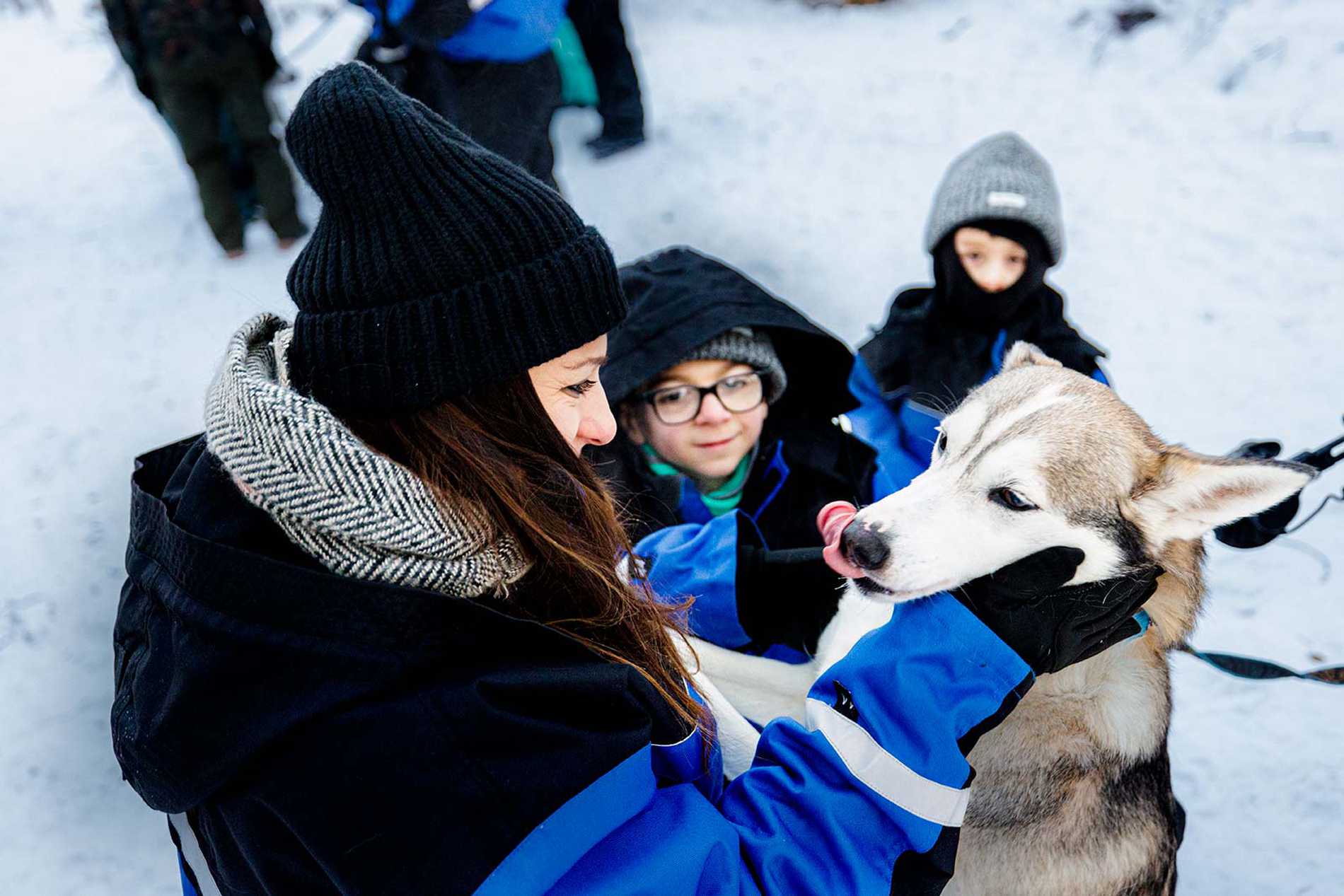 Jack's mum pets one of the husky pups as the children watch on.