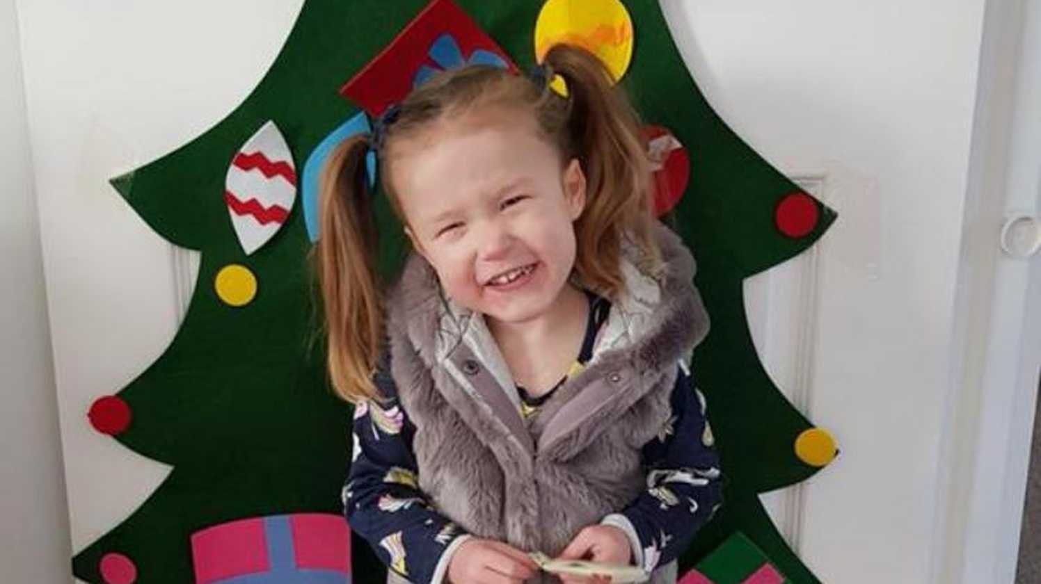 Wish child Hope smiling in front of a Christmas tree