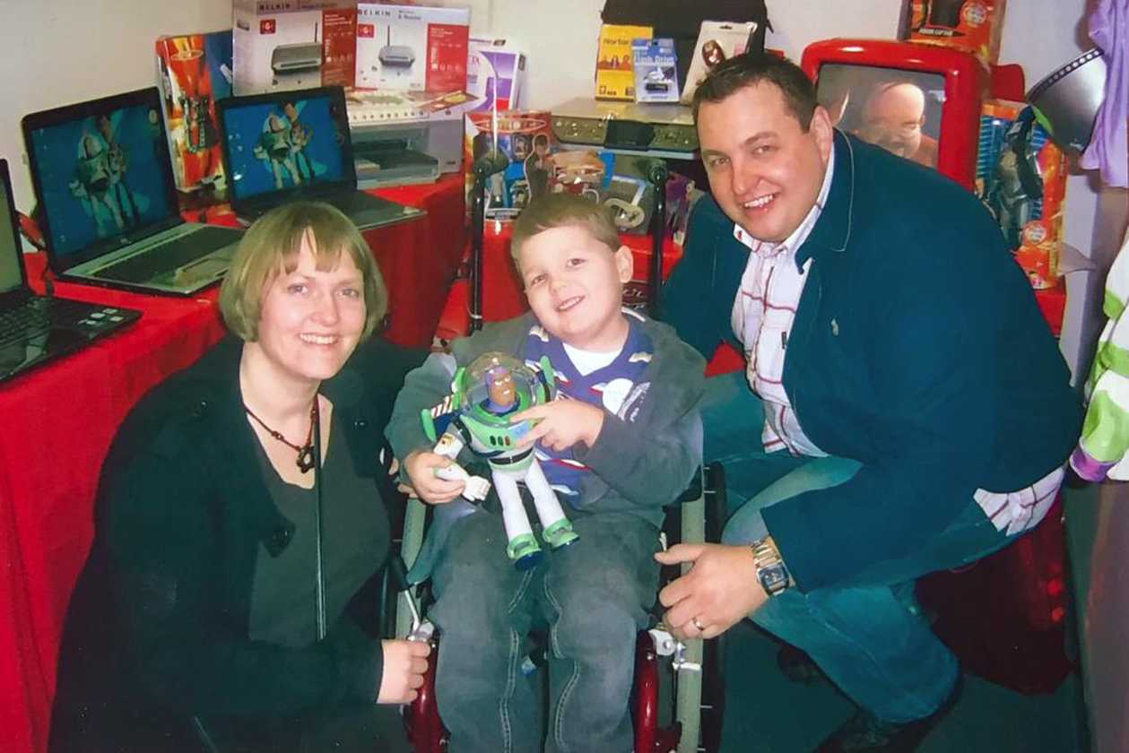 Jacob, holding a Buzz Lightyear doll, with his mum and dad.